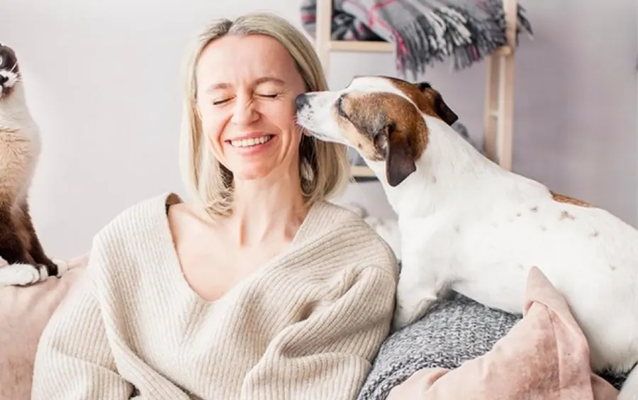 A woman with her dog and cat on the sofa